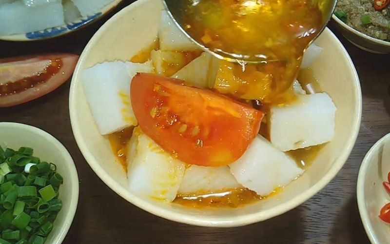 Cho phần bánh đúc đã hấp vào một tô lớn, chan phần nước lèo nóng hổi lên